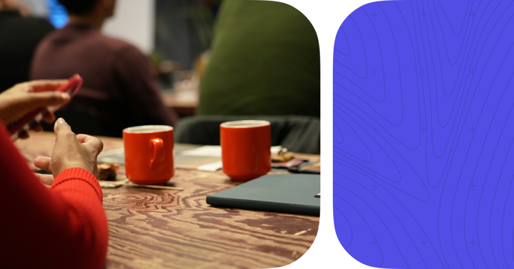 2 coffee cups on a wooden table. A women's hands in the frame.